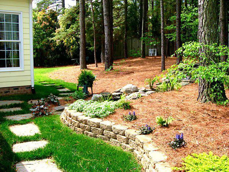 Photo of a hardscaped rock waterfall with plants and slate pathway